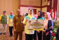 Ketua TP-PKK Provinsi Kepulauan Riau Dewi Kumalasari Ansar, menyerahkan bantuan dana kepada kader posyandu di sela Kegiatan Workshop Peningkatan Kompetensi Kader Posyandu bertempat di Aula Wan Sri Beni, Dompak Tanjungpinang, Senin (29/7/2024). Matapedia6.com/Diskominfo