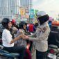 Anggota Ditlantas Polda Kepri saat memberikan bingkisan bunga kepada pengendara yang sudah tertib berlalu lintas di Simpang Frengky Kota Batam, Jumat (14/2/2025). Matapedia6.com/Dok Humas Polda