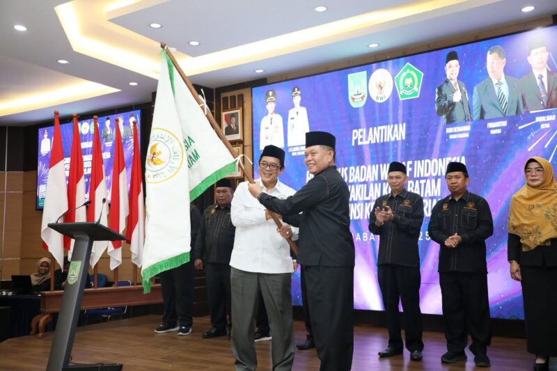 Ketua BWI Batam Buralimar mengibarkan bendera petaka usai dilantik sebagai ketua oleh Wakil Ketua BWI Pusat, Tatang Astarudin di lantai IV Kantor Wali Kota Batam, Rabu (13/8/2025). Matapedia6.com/Diskominfo