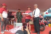 Ketua RW pasar Aviari Abun saat menyerahkan hadiah sepeda motor kepada pemenang undian pesta HUT ke-80 RI di pasar Aviari, Sabtu (30/8/2025). Matapedia6.com/Rega