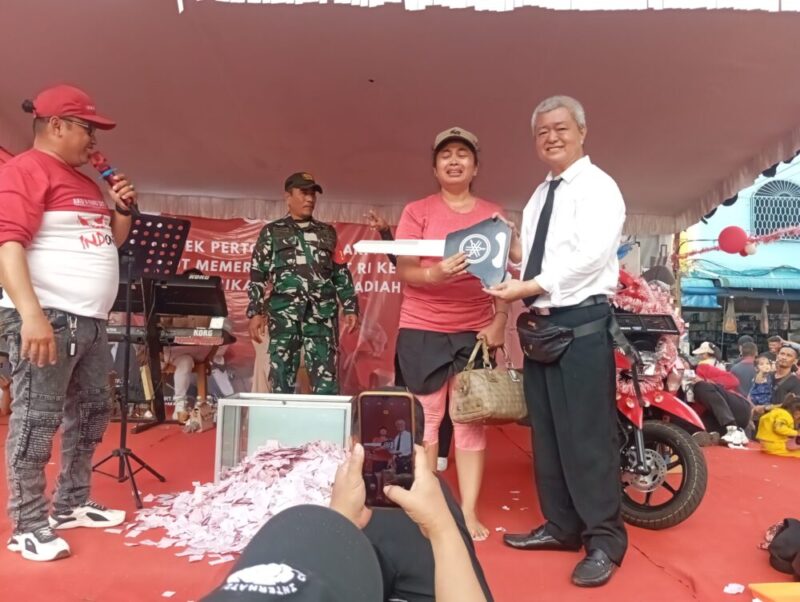 Ketua RW pasar Aviari Abun saat menyerahkan hadiah sepeda motor kepada pemenang undian pesta HUT ke-80 RI di pasar Aviari, Sabtu (30/8/2025). Matapedia6.com/Rega